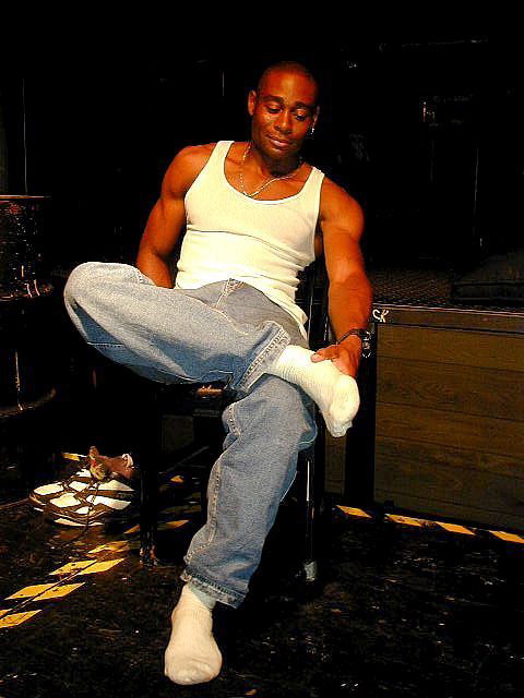 handsome black muscle hunk in white tank top and white socks