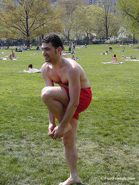 Holding his bare foot in public park