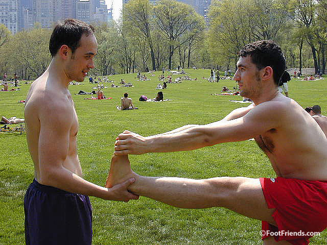 Amateur guy holding pal's bare foot in public